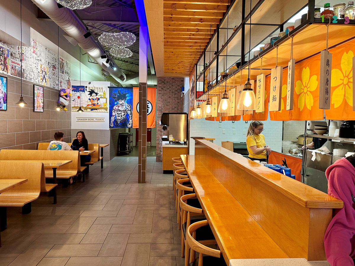 inside restaurant with brown tables and chairs and dragon ball posters